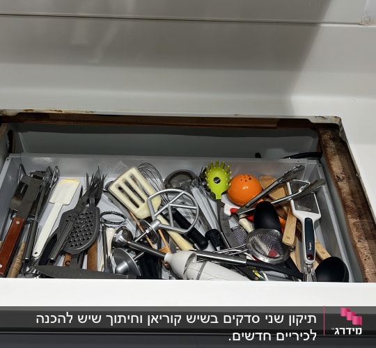 משטח שיש לבן עם מגירה פתוחה מלאה בכלי מטבח